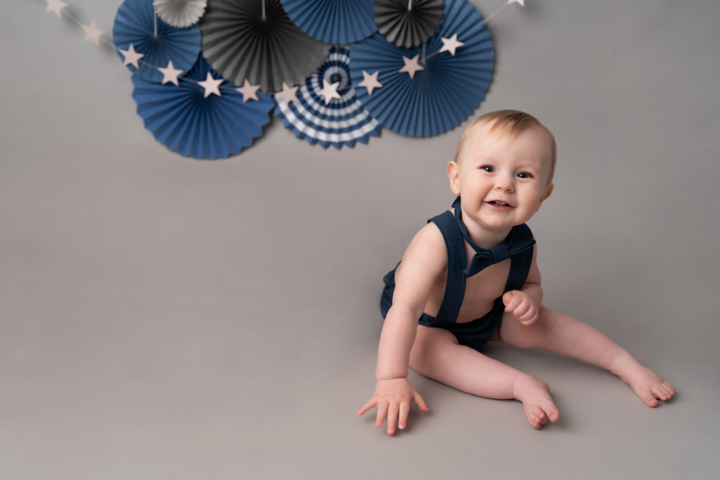 chester baby photography expert photographs boy smiling on grey and blue birthday set