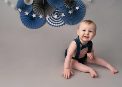 chester baby photography expert photographs boy smiling on grey and blue birthday set