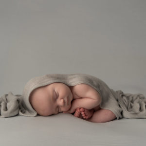 newborn photographer, baby boy sleeping curled up in a grey wrap