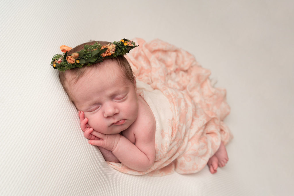 photographing baby at home, little newborn girl in a flower crown sleeping peacefully