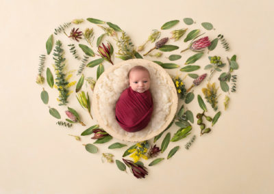 Gorgeous heart made of flowers with a baby wrapped in dark red in a bowl at the centre. Taipei baby photographer