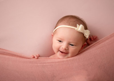 Baby girl in pink with a cream bow has a big smile for Taipei baby photographer Cass Davies
