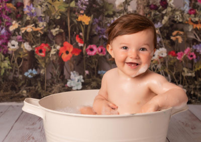 1st birthday photoshoot baby girl splashes in vintage tub