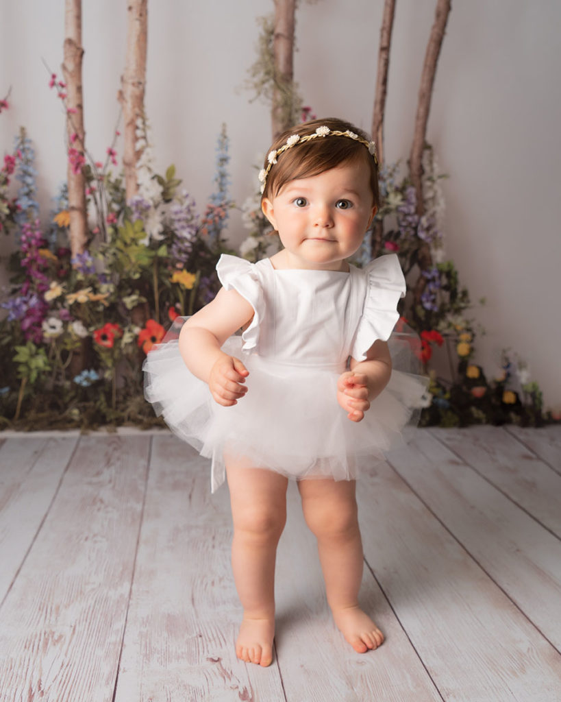 1st birthday portrait of little girl in white at Cass Davies Photography cake smash studio