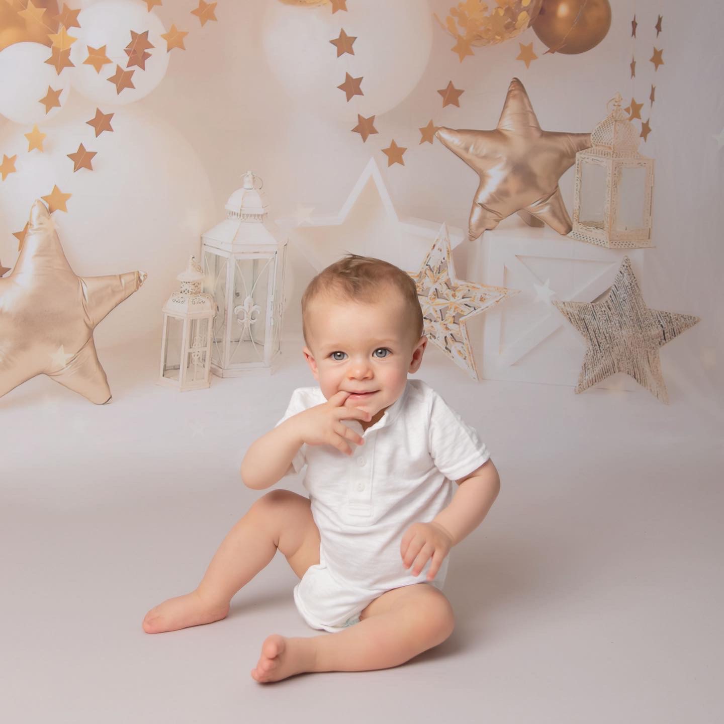 Portrait image of a baby on a gold and white set part of a cake smash taipei